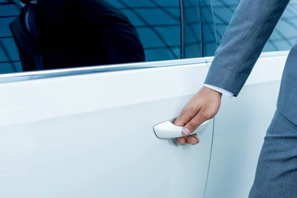 Обрезанный снимок бизнесмена, открывающего дверь машины на улице — стоковое фото
