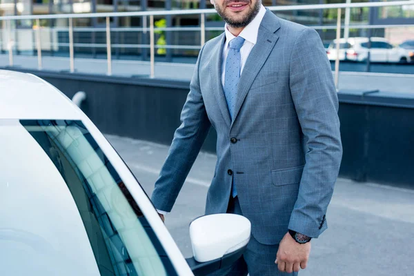 Обрезанный снимок бизнесмена, стоящего рядом с машиной на парковке — стоковое фото