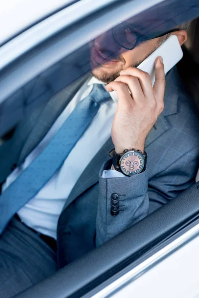 Partial view of smiling businessman in eyeglasses talking on smartphone while driving car — Stock Photo