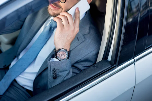 Partial view of businessman talking on smartphone while driving car — Stock Photo