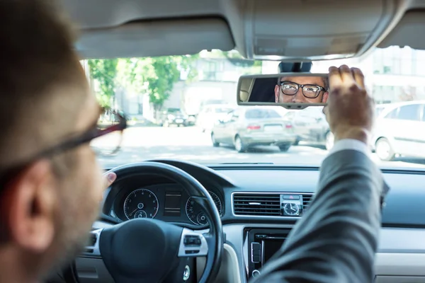 Vue partielle de l'homme d'affaires en lunettes regardant le rétroviseur en voiture — Photo de stock