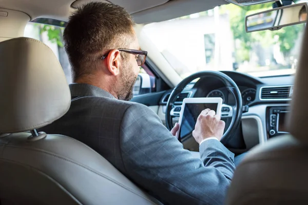 Частичный взгляд бизнесмена в очках с помощью планшета в автомобиле — стоковое фото