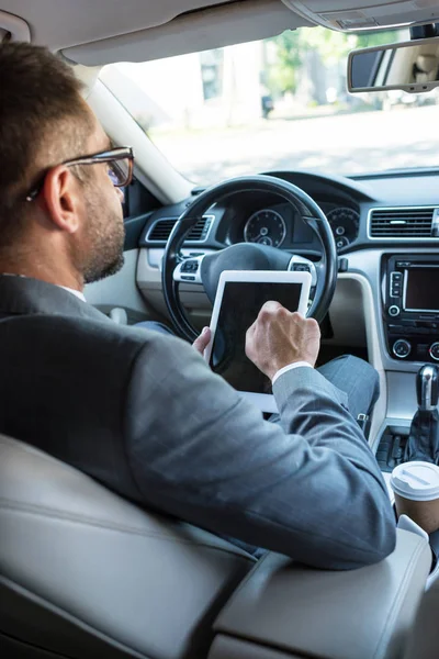 Partial view of businessman in eyeglasses using tablet in car — Stock Photo
