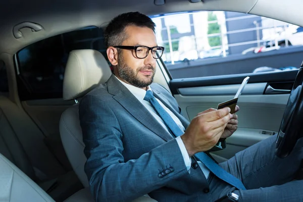 Side view of businessman with tablet and credit card sitting in car — Stock Photo