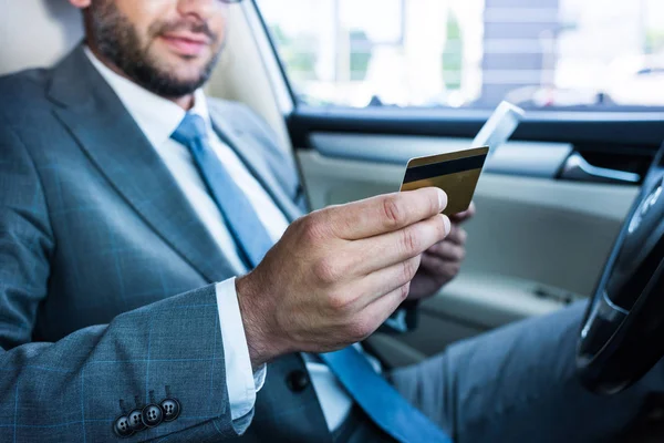 Partial view of businessman with tablet and credit card sitting in car — Stock Photo