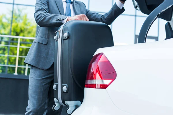 Teilansicht von Geschäftsmann, der Gepäck in Auto auf Parkplatz legt — Stockfoto
