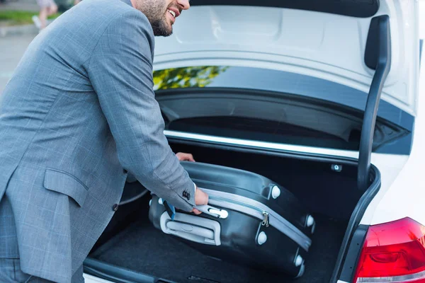 Tiro cortado de homem de negócios colocando bagagem no carro no estacionamento — Fotografia de Stock
