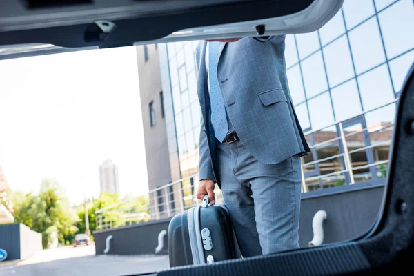 Teilansicht eines Geschäftsmannes mit Gepäck, der am Auto auf dem Parkplatz steht — Stockfoto
