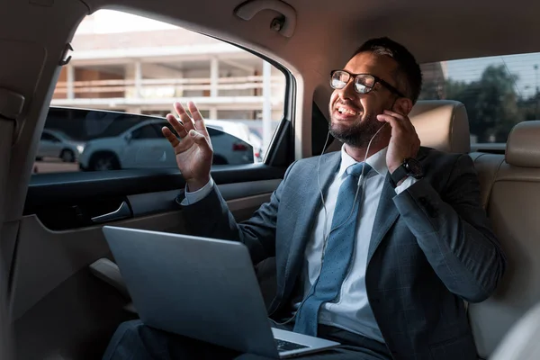 Geschäftsmann mit Kopfhörer und Laptop hört Musik im Auto — Stockfoto