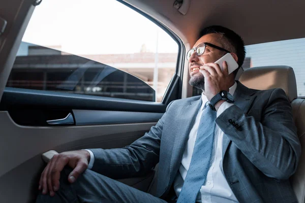 Uomo d'affari che parla su smartphone sul sedile posteriore in auto — Foto stock