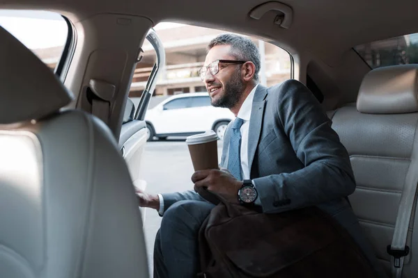 Geschäftsmann mit Coffee to go bei geöffneter Tür im Auto sitzen — Stockfoto