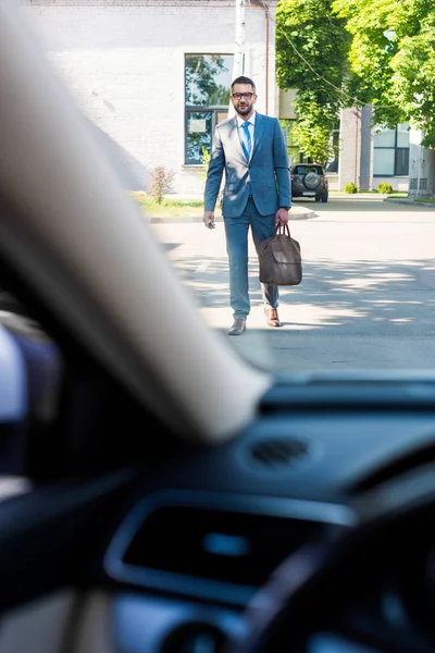 Uomo d'affari in giacca e cravatta e occhiali che va in macchina per strada — Foto stock