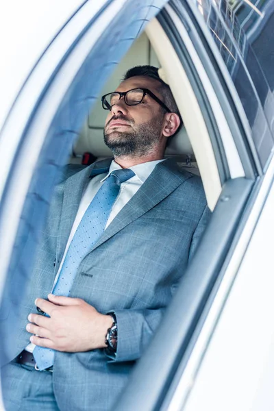 Hombre de negocios cansado en gafas que duermen en coche - foto de stock