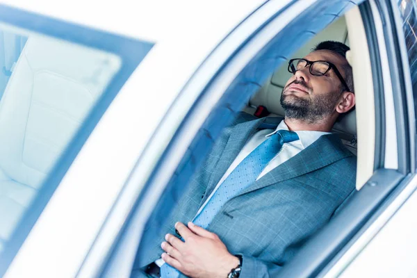 Уставший бизнесмен в очках спит в машине — стоковое фото