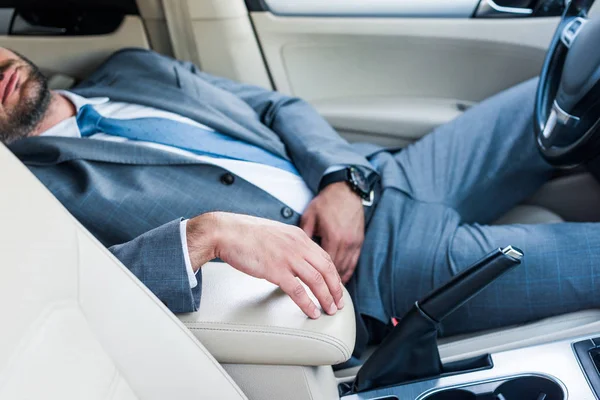 Recortado disparo de cansado hombre de negocios durmiendo en coche - foto de stock