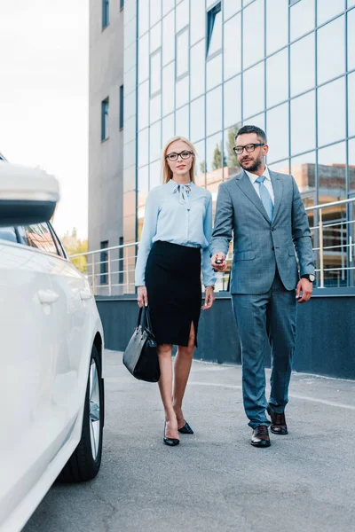 Gente de negocios en gafas graduadas caminando a coche en el aparcamiento - foto de stock