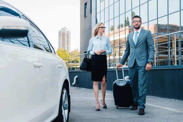 Les gens d'affaires avec des bagages marchant à la voiture sur le parking — Photo de stock