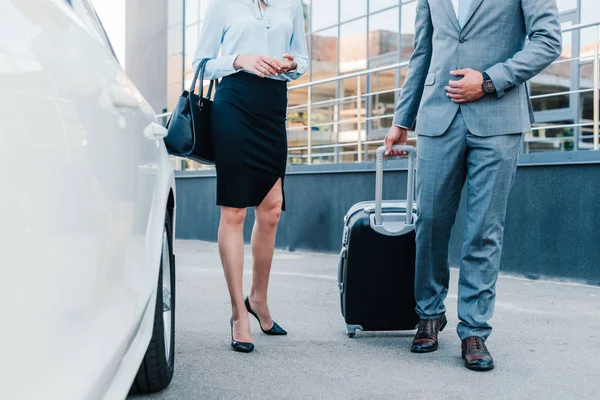 Partial view of business people with luggage walking to car on parking — Stock Photo