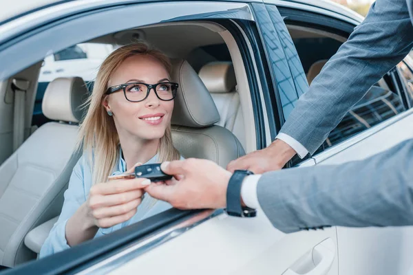 Partial view of businessman giving car keys to smiling colleague at driver seat in car — Stock Photo