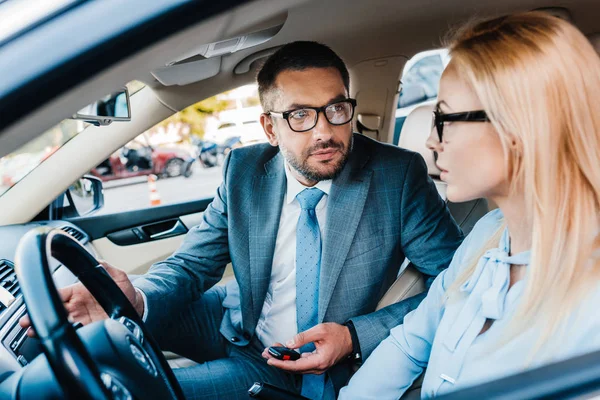 Enfoque selectivo de los colegas de negocios mirándose en el coche - foto de stock