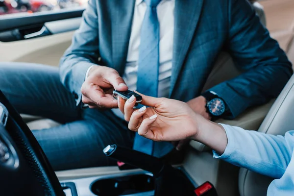 Обрізаний знімок бізнесмена, що дає ключі від автомобіля колезі на водійському сидінні в машині — стокове фото