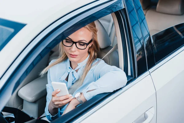 Retrato de mulher de negócios em óculos usando smartphone no carro — Fotografia de Stock