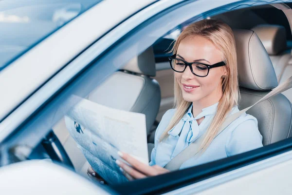 Donna d'affari sorridente che legge il giornale in automobile — Foto stock