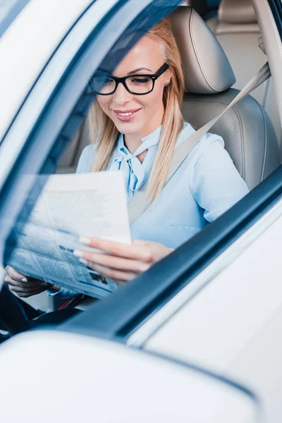 Donna d'affari sorridente che legge il giornale in automobile — Foto stock