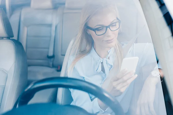Портрет бізнес-леді в окулярах з використанням смартфона в машині — стокове фото