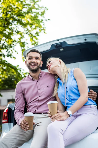 Portrait of smiling couple with coffee to go sitting on car together — Stock Photo