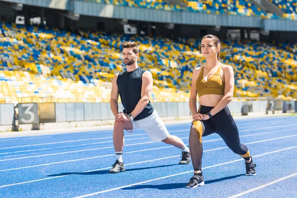 Jovem casal ajuste aquecimento antes do treinamento em pista de corrida no estádio de esportes — Fotografia de Stock