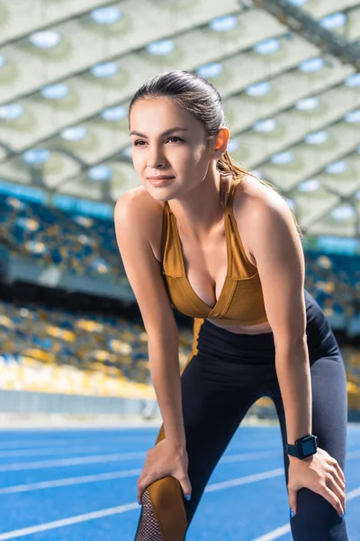 Apto jovem mulher descansando depois de correr na pista de corrida no estádio de esportes — Fotografia de Stock