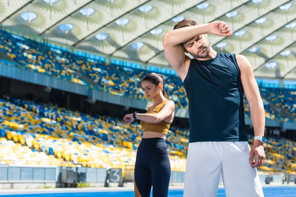Exhausted couple standing on running track at sports stadium after jogging — Stock Photo