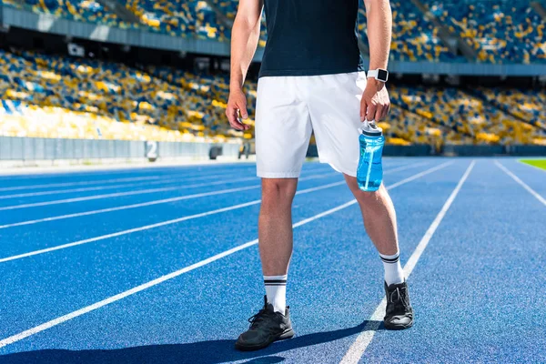 Plan recadré de sportif avec bouteille d'eau de fitness au stade de sport — Photo de stock