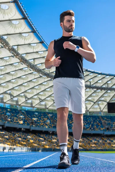 Vista inferior del joven en forma haciendo ejercicio en pista de atletismo en el estadio deportivo - foto de stock