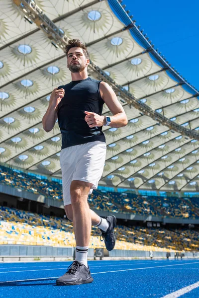 Bottom view of sporty young man exercising on running track at sports stadium — Stock Photo