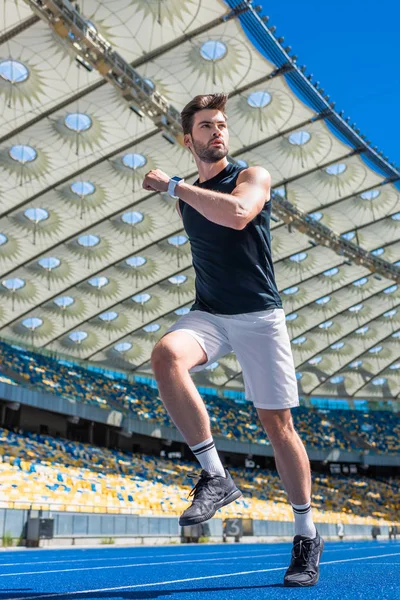 Vista inferior del joven atlético haciendo ejercicio en pista de atletismo en el estadio deportivo — Stock Photo