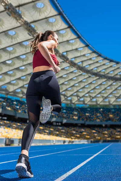 Bottom view of sportive young woman running on track at sports stadium — Stock Photo