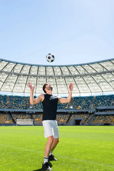 Deportivo joven jugador de fútbol rebotando pelota en la cabeza en el estadio de deportes - foto de stock