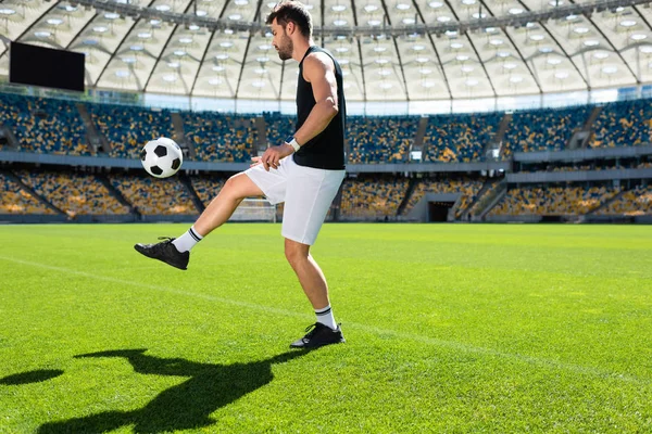 Desportivo jovem jogador de futebol saltando bola na perna no estádio de esportes — Fotografia de Stock