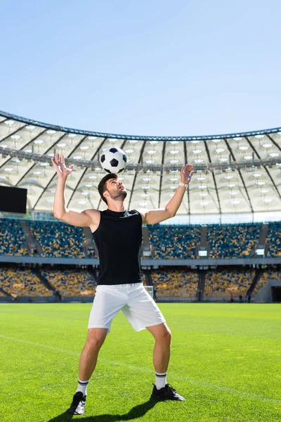 Schöne junge Fußballerin balanciert Ball auf Kopf im Sportstadion — Stockfoto