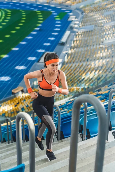 Vista de ángulo alto de la joven deportista corriendo arriba en el estadio de deportes - foto de stock
