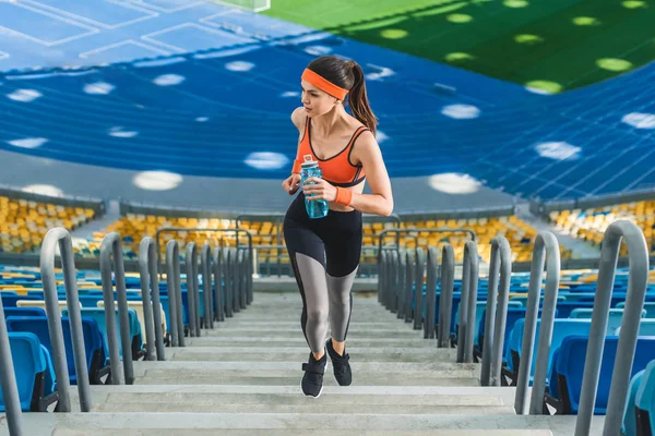 Vista de ángulo alto de mujer joven atractiva corriendo arriba en el estadio de deportes - foto de stock