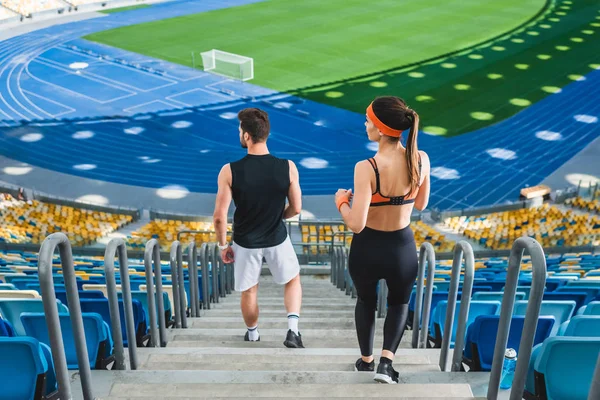 Vista de ángulo alto de la joven pareja deportiva caminando abajo en el estadio de deportes - foto de stock