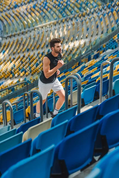 Attractive young man jogging upstairs at sports stadium — Stock Photo