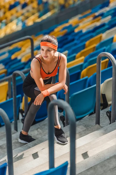 Высокий угол обзора измученной спортивной женщины, отдыхающей на лестнице на спортивном стадионе — стоковое фото