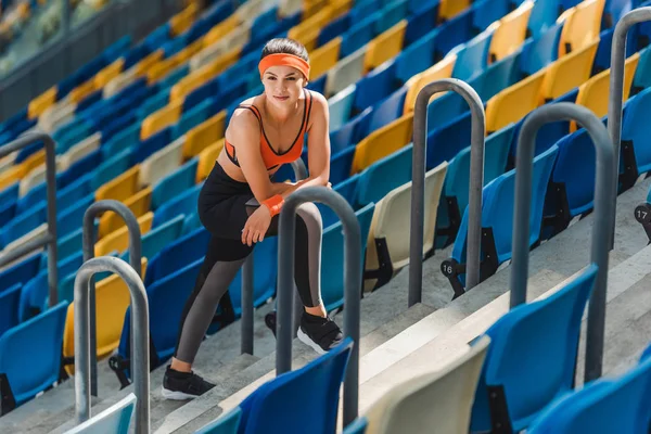 Vista de ángulo alto de la mujer en forma agotada relajarse en las escaleras en el estadio deportivo - foto de stock