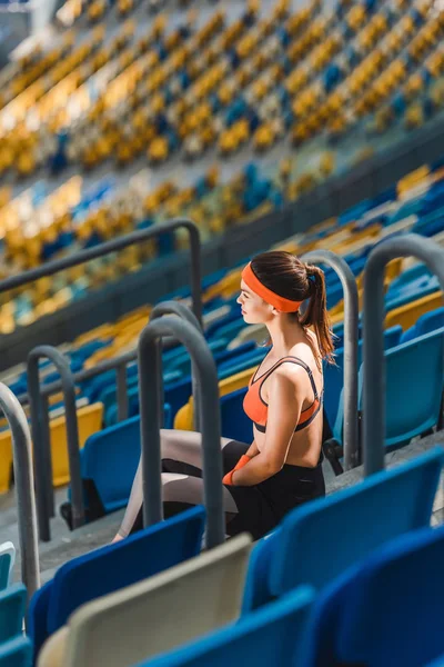 Высокий угол обзора красивой молодой женщины, отдыхающей на лестнице на спортивном стадионе — стоковое фото