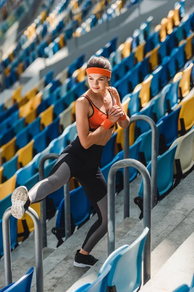 Blick aus der Vogelperspektive auf die sportliche junge Frau, die sich auf den Tribünen des Sportstadions dehnt — Stockfoto