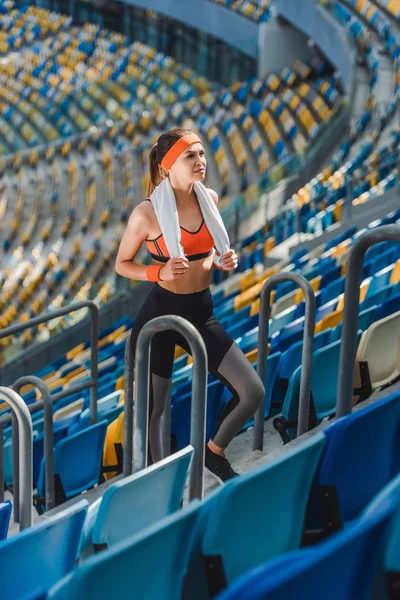 Vista de ángulo alto de la atractiva mujer joven con toalla en el estadio deportivo - foto de stock